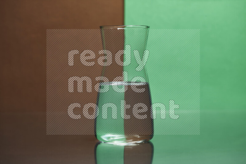 The image features a clear glassware filled with water, set against brown and green background