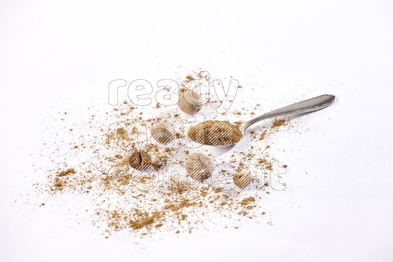A metal spoon full of nutmeg powder with nutmeg powder and seeds beside it on a white flooring in different angles