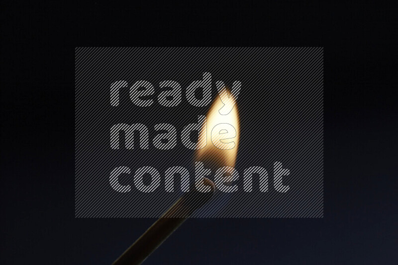 A burning matchstick isolated on dark backdrop