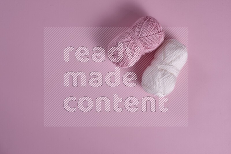 A white and pink collection of sewing and tailoring tools arranged on a pink background