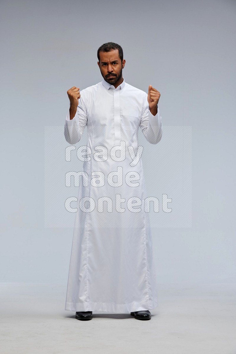 Saudi man Wearing Thob standing interacting with the camera on Gray background