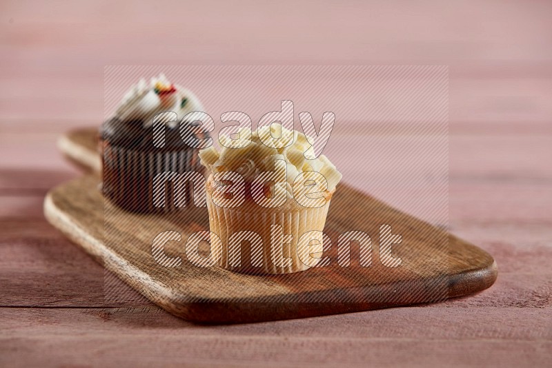 Vanilla mini cupcake topped with white chocolate curls on a wooden board