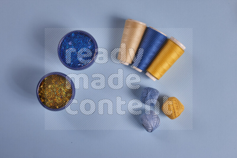 مجموعة من أدوات الخياطة والتفصيل صفراء وزرقاء اللون على خلفية زرقاء