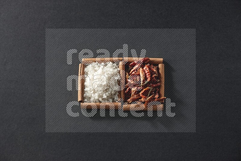 2 squares of cinnamon sticks full of chilis and salt on black flooring