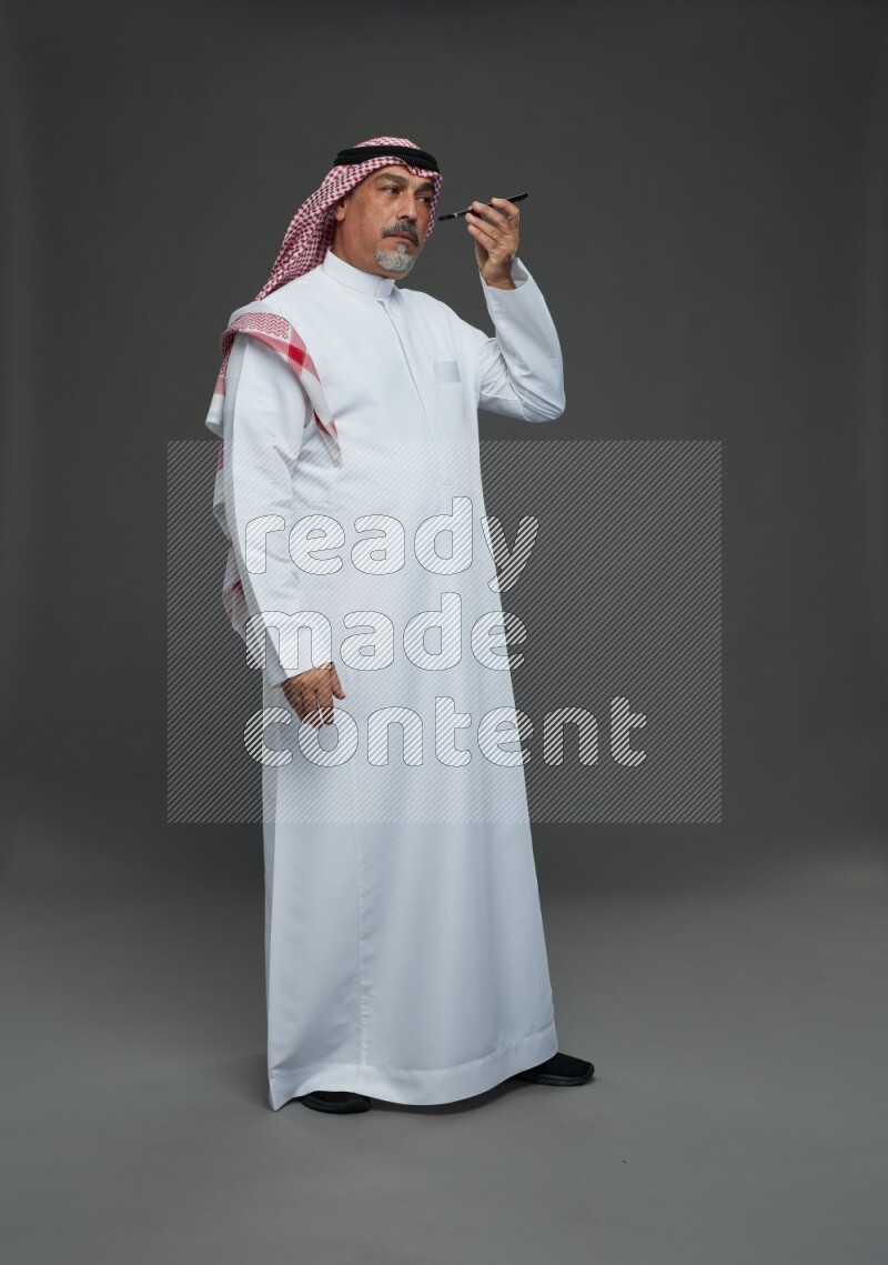 Saudi man with shomag Standing talking on phone on gray background