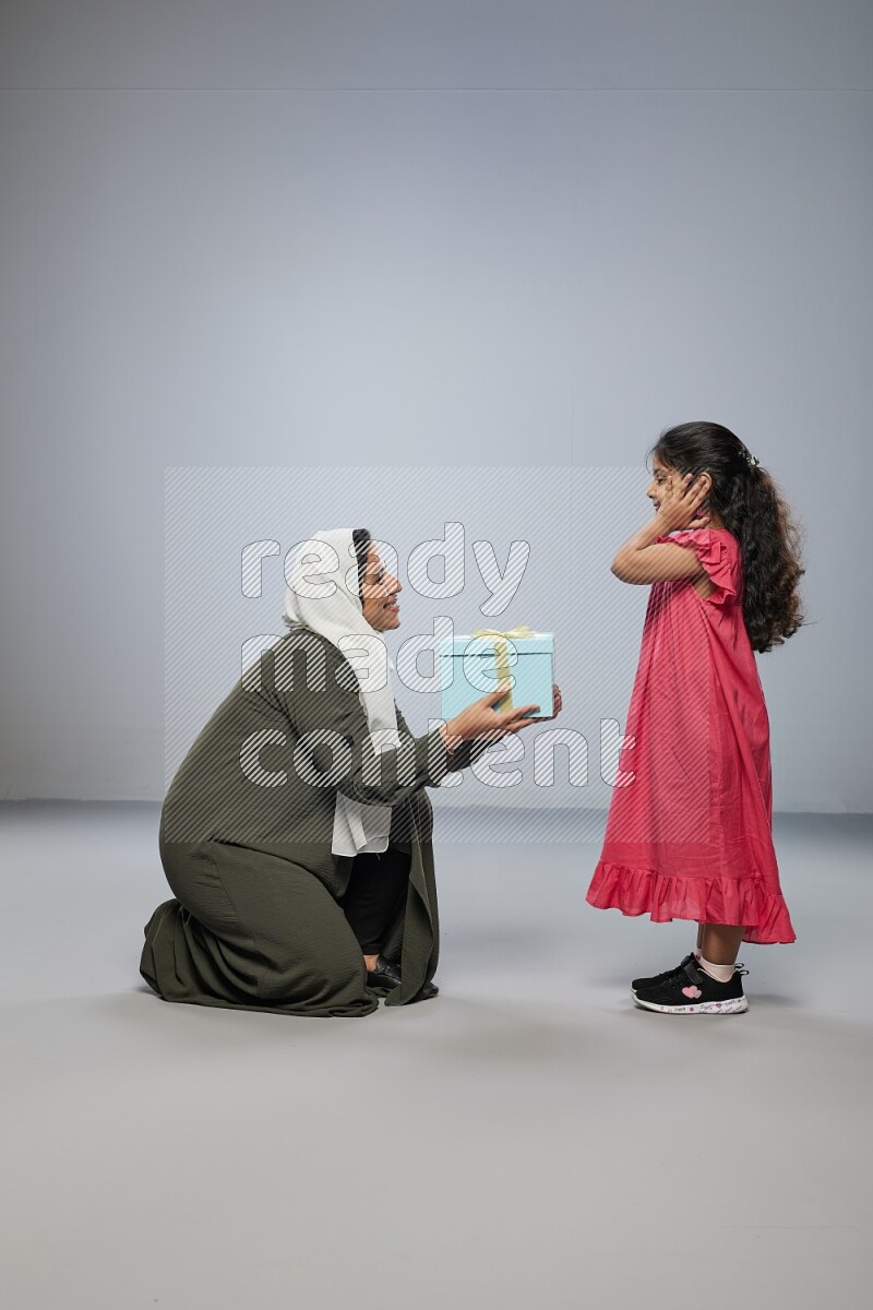 A girl giving a gift to her mother on gray background