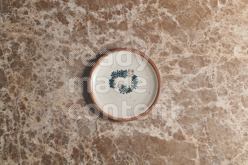 A decorative pottery plate on beige marble background