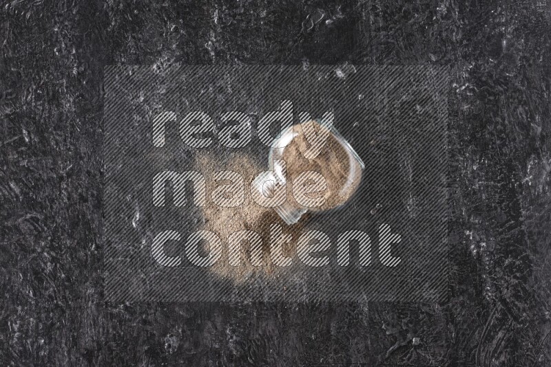 بودرة الفلفل الأسود في وعاء زجاجي مقلوب علي خلفية سوداء