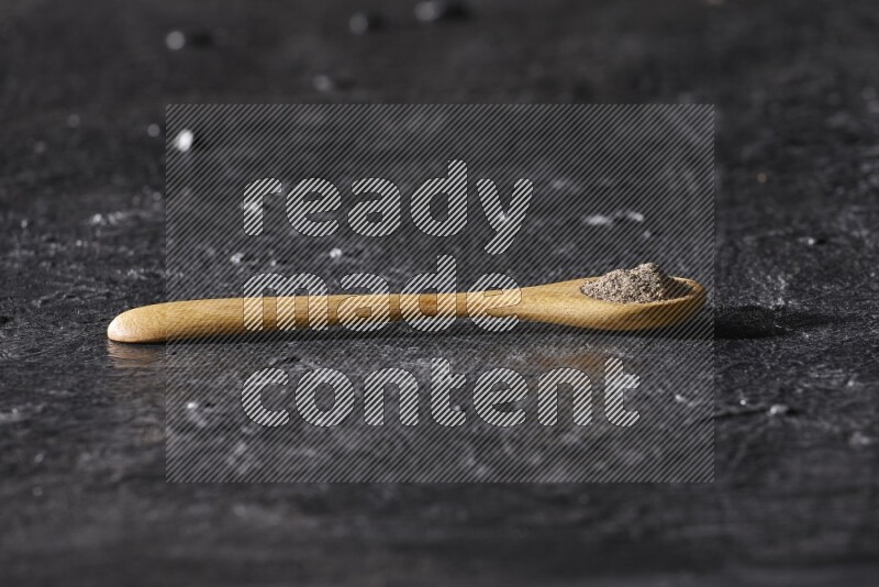 حبوب الفلفل الأسود في ملعقة خشبية علي خلفية سوداء