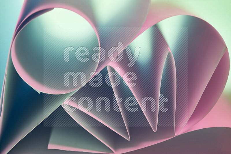 عرض فني لطيات الورق تخلق مزيج من الأشكال الهندسية، مضاءة بإضاءة ناعمة بدرجات اللون الأخضر والوردي