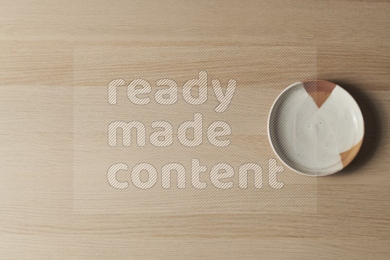 صحن فخاري متعدد الألوان على خلفية خشبية فاتحة