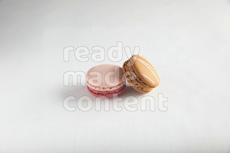 45º Shot of of two assorted Brown Irish Cream, and Pink Litchi Raspberry macarons on white background