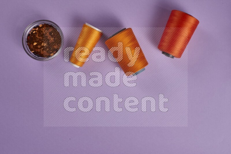 مجموعة من أدوات الخياطة والتفصيل برتقالية اللون على خلفية أرجوانية