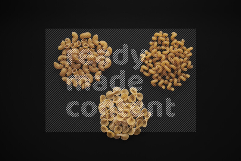 Different pasta types in bunches on black background