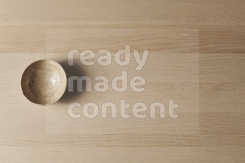 A multicolored pottery bowl on light wooden background