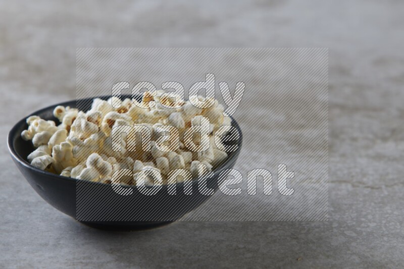 popcorn in black bowl on a grey textured countertop