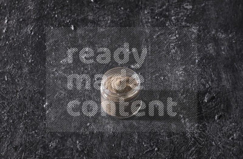 بودرة الفلفل الأسود في وعاء زجاجي علي خلفية سوداء