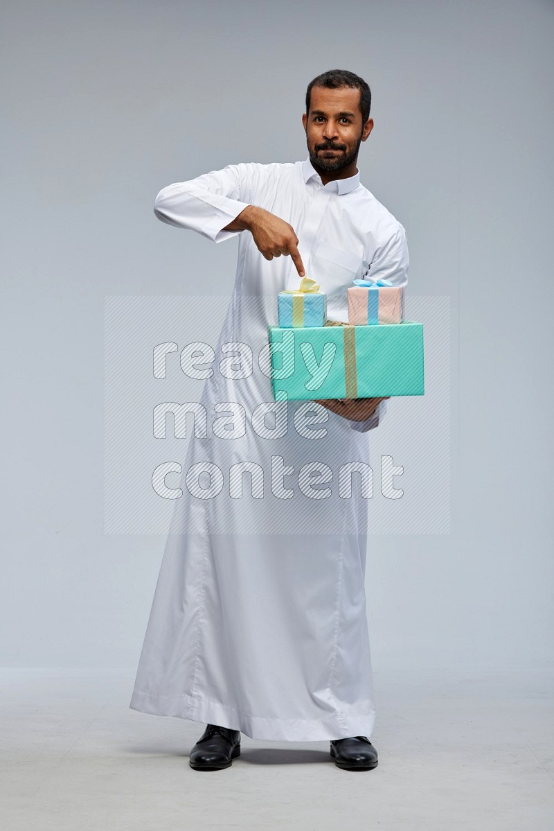 Saudi man Wearing thob standing holding gift box on Gray background