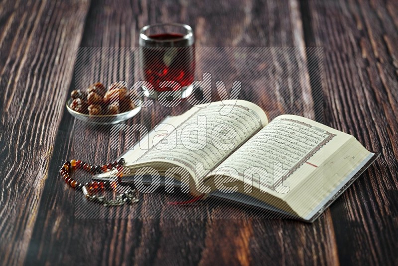 Quran with dates, prayer beads and different drinks all placed on wooden background