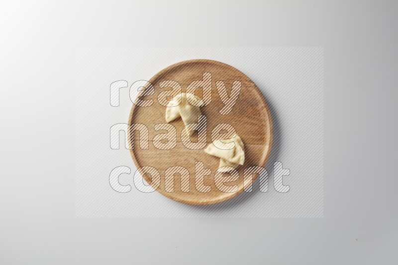 Four Sambosas on a wooden round plate on a white background