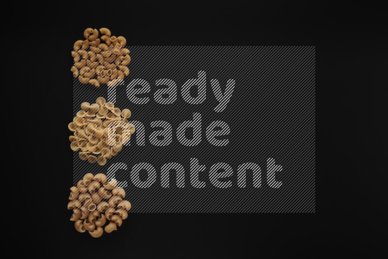 Different pasta types in 3 bunches on black background