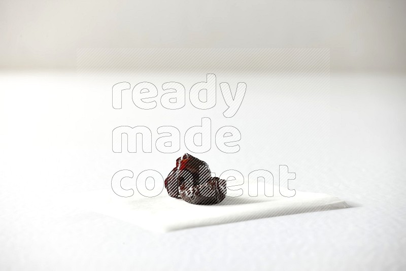 Two dried plums on a piece of paper on a white background in different angles