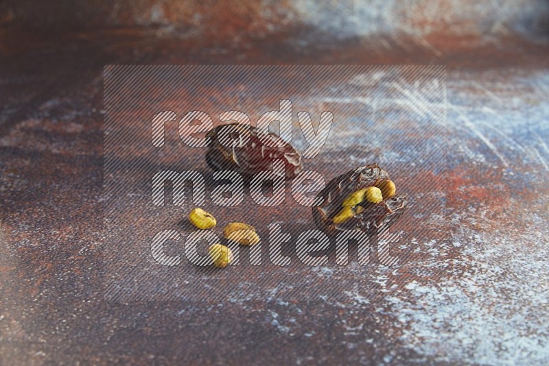 two pistachio stuffed madjoul dates on a rustic reddish background