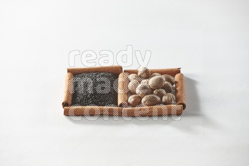 2 squares of cinnamon sticks full of black seeds and nutmeg on white flooring