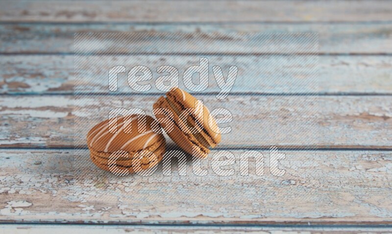 45º Shot of two Brown Irish Cream macarons on a  light blue wooden background
