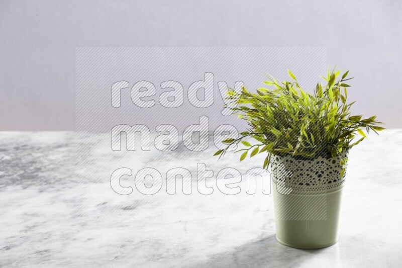 Artificial plant in green decorative pot on grey marble background