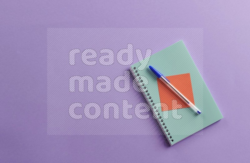 A blue note book with school supplies on purple background (Back to school)
