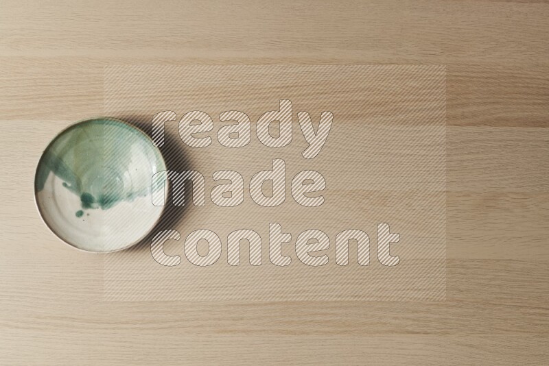 صحن فخاري متعدد الألوان على خلفية خشبية فاتحة