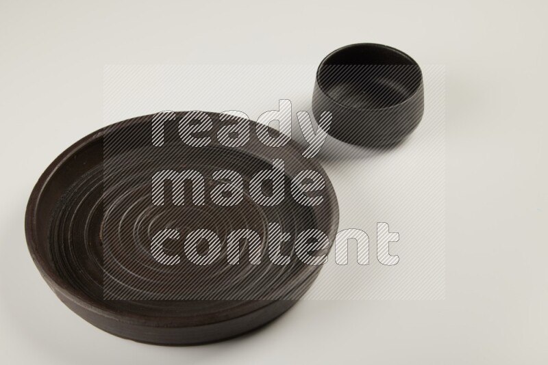 black pottery plate and black bowls on white background