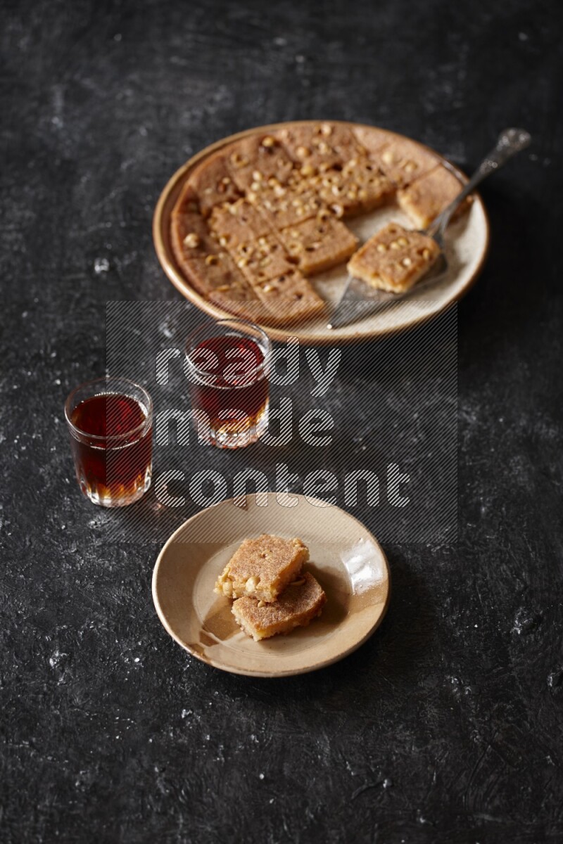 Basbousa with tea in a dark setup