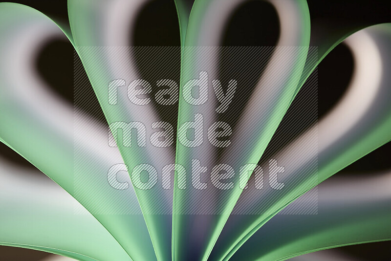 An abstract art piece displaying smooth curves in white and green gradients created by colored light