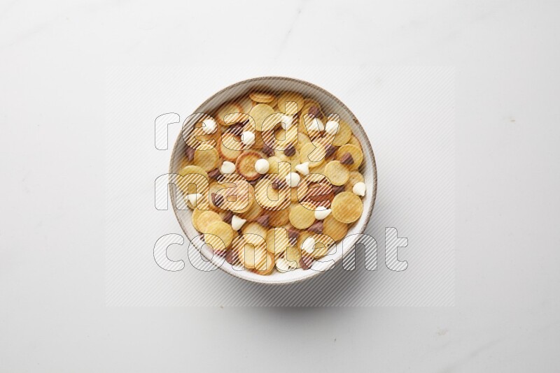 Top-view shot of mixed chocolate chips cereal pancakes in a round bowl on white background
