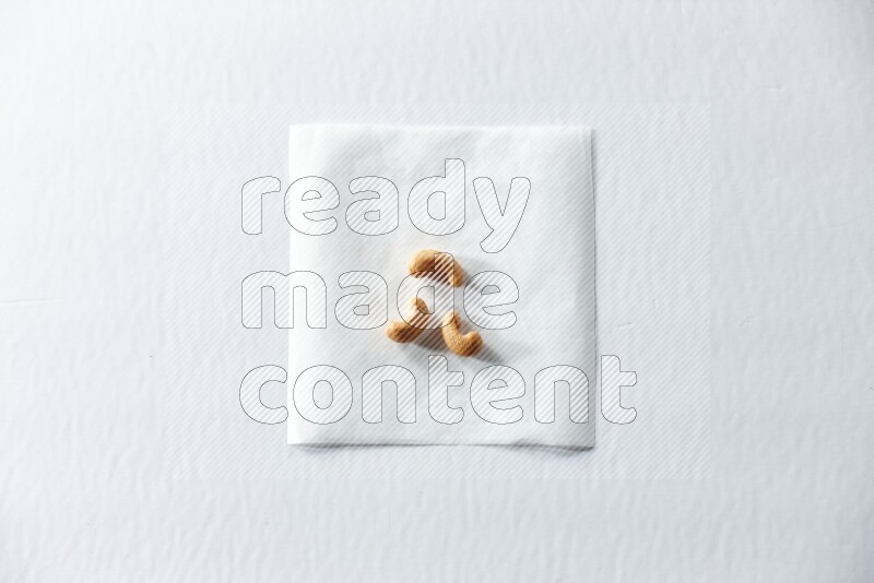 3 cashews on a piece of paper on a white background in different angles