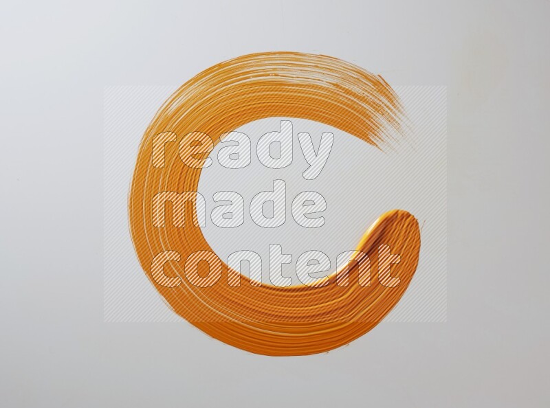 An orange circular painting brush stroke on white background