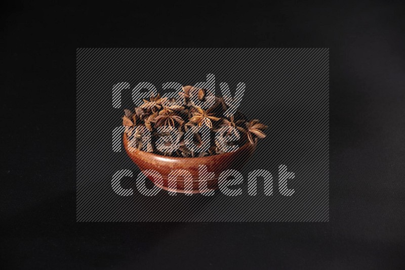 Star Anise in a wooden bowl on black flooring