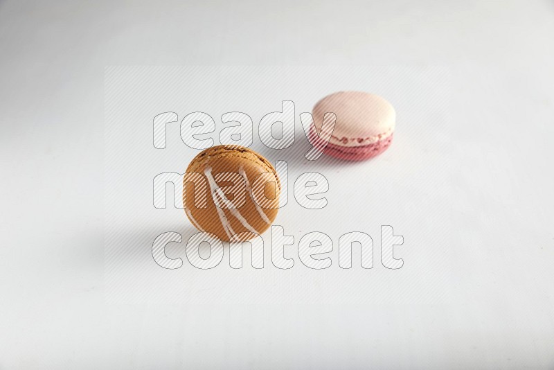 45º Shot of of two assorted Brown Irish Cream, and Pink Litchi Raspberry macarons on white background