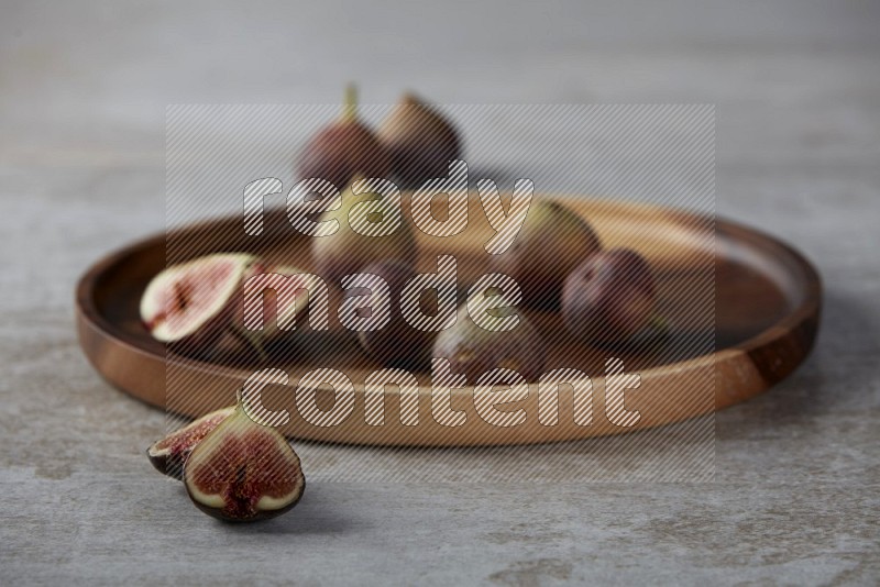 Fresh Figs on a wooden board on a textured grey background
