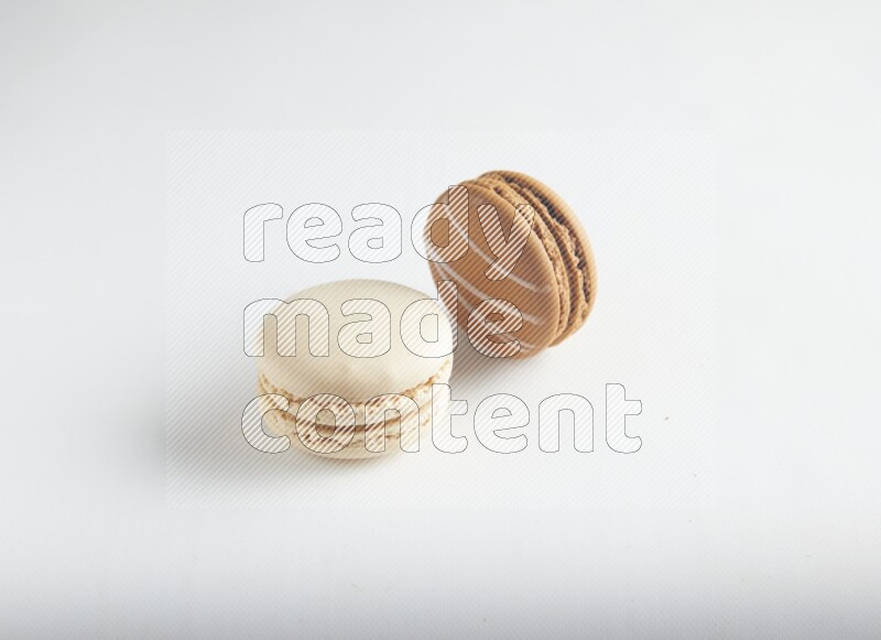 45º Shot of of two assorted Brown Irish Cream, and White Caramel fleur de sel macarons on white background
