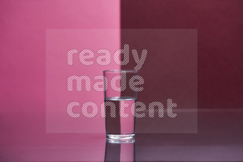 The image features a clear glassware filled with water, set against pink and dark red background