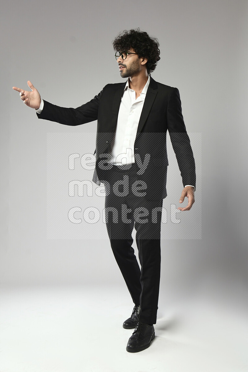 A man wearing formal standing and making a hand gesture on white background