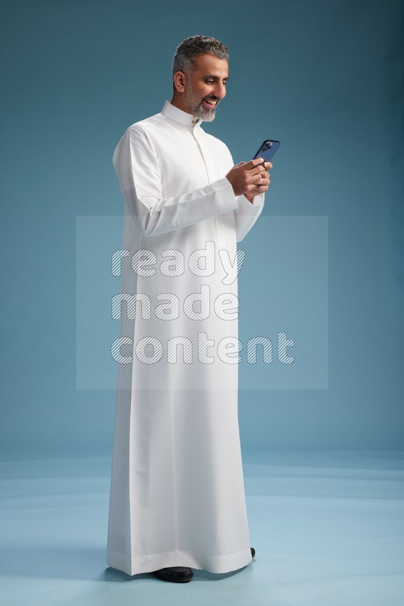 Saudi man waring thob texting on blue background