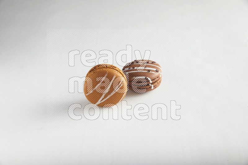 45º Shot of of two assorted Brown Irish Cream, and Brown white Chocolate Caramel macarons on white background