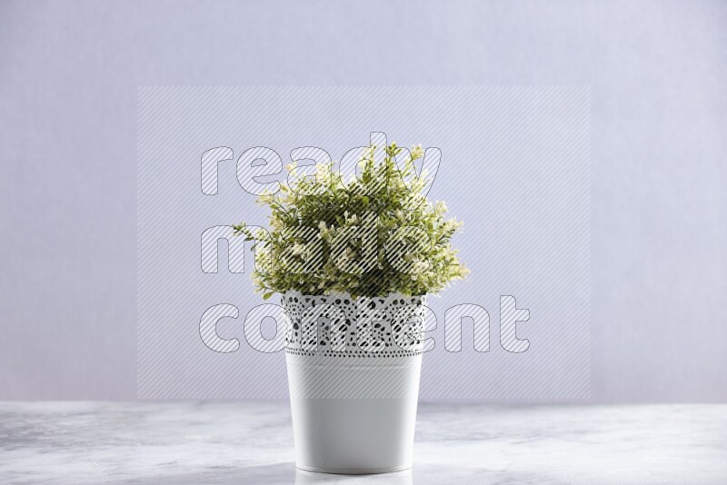 Artificial plant in white decorative pot on grey marble background