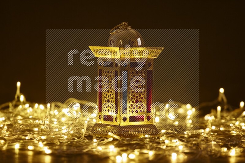 A traditional ramadan lantern surrounded by glowing fairy lights in a dark setup