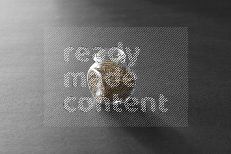 كمون في وعاء زجاجي علي خلفية سوداء