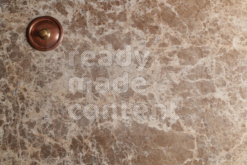A small copper pot on beige marble background